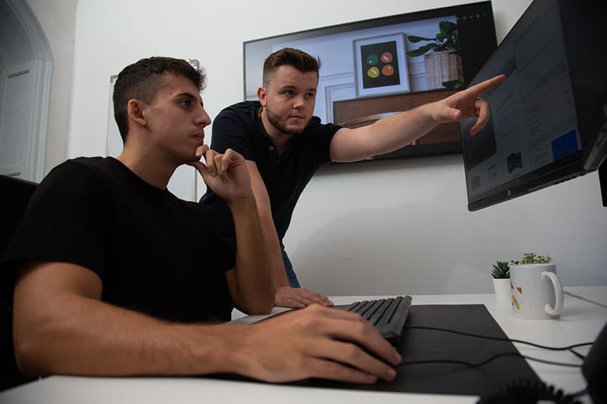 Twee collega's van Selva Digital bekijken samen een website op een monitor op kantoor