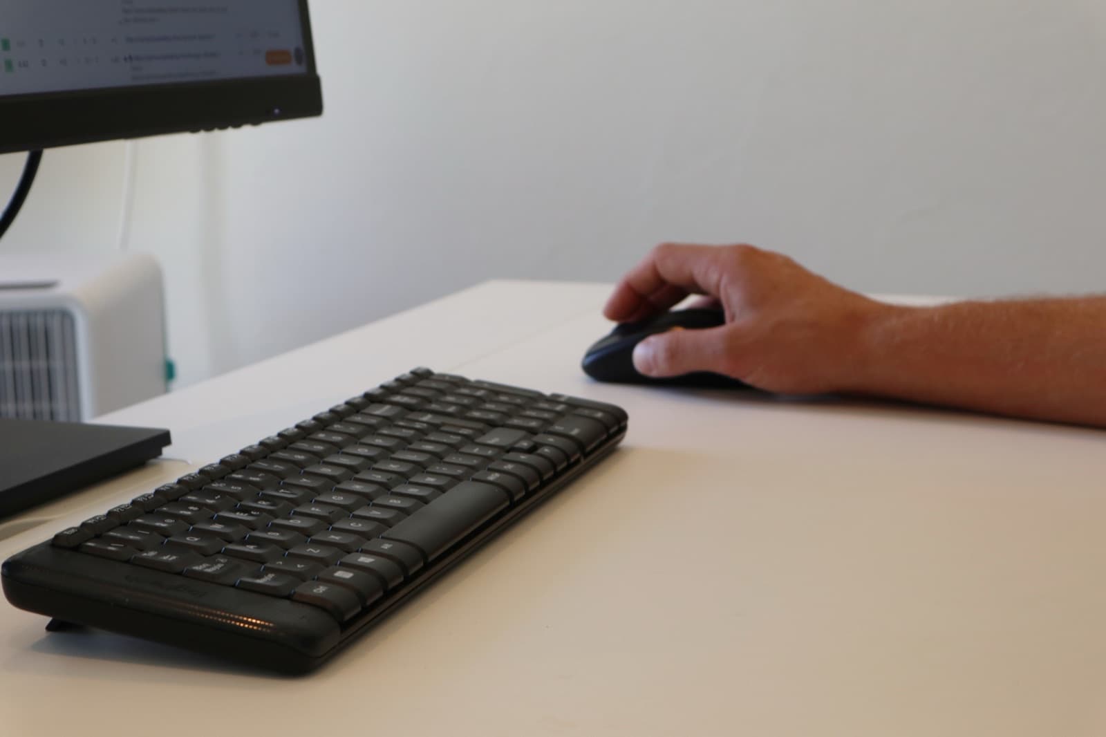 A hand on the mouse, keyboard in front, work on the screen